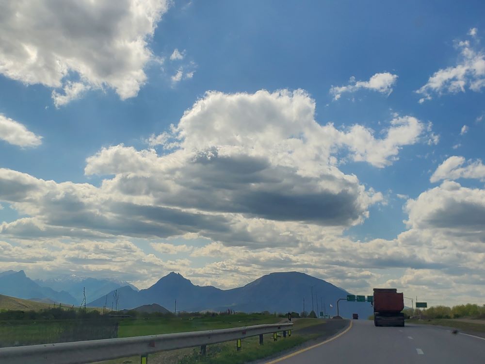 une route avec de hautes montagnes au loin, un camion et des nuages au kurdistan iranien