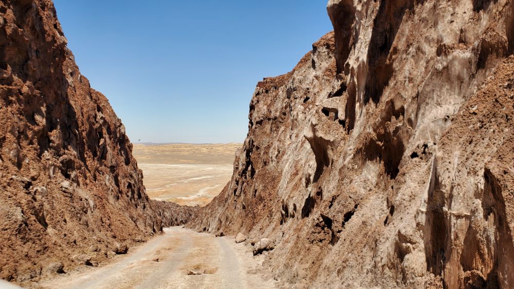une route de terre en Iran enserrée par la roche, dans les tons ocres, dans la région de Qom