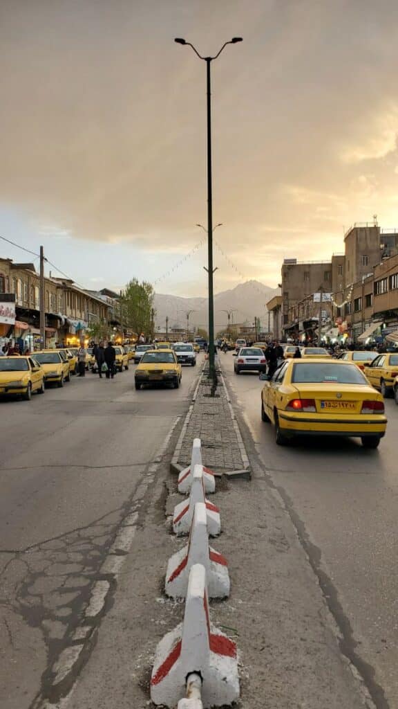 une rue d'Hamedan en Iran, pleine de taxis jaunes, à la lumière du soir