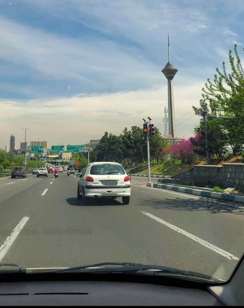 grand axe arrivant sur téhéran avec la tour milad et des voitures à cheval sur deux lignes