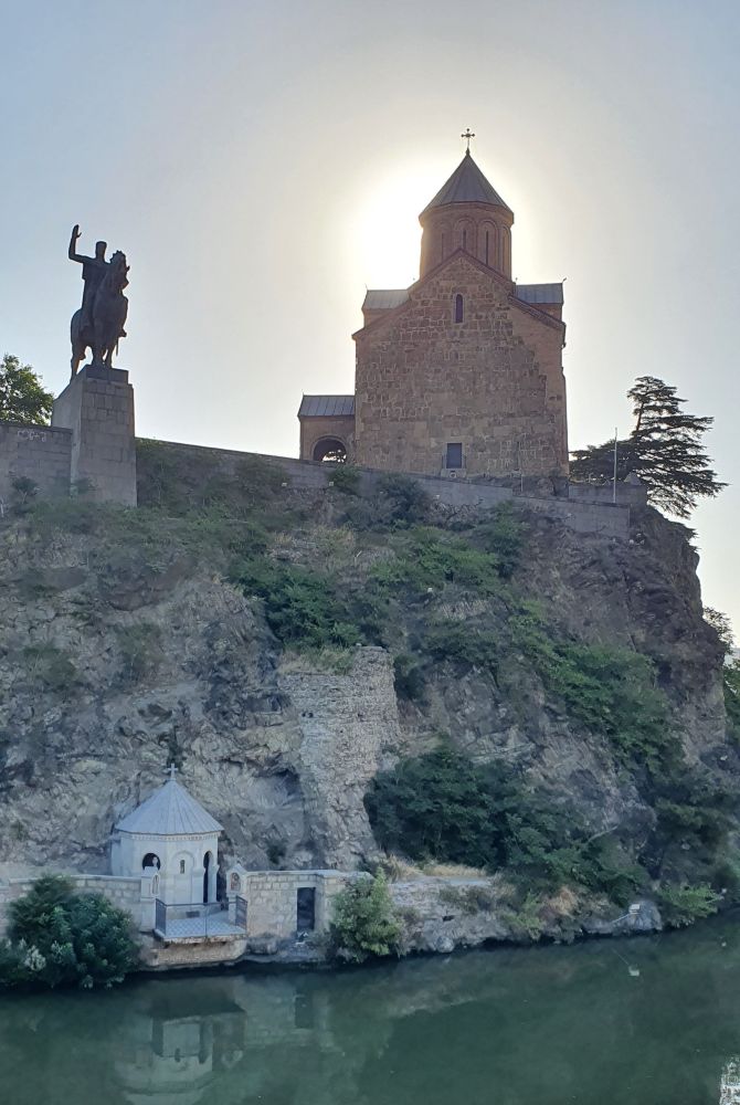 vue de l'église Metekhi avec la statue de Vakhtang Goergassali à cheval et une chapelle en contre-bas, au bord de la Koura